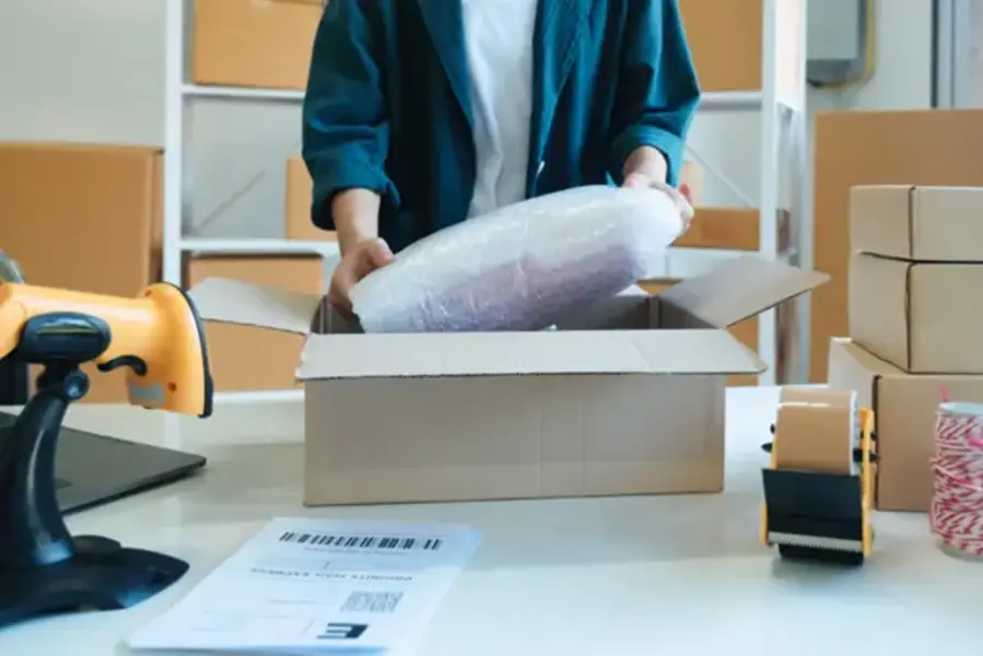 A courier carefully placing a package into a box