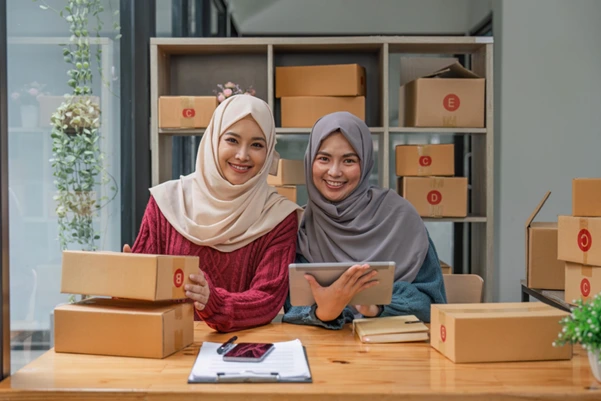 Two women carefully preparing and boxing gifts for international shipping